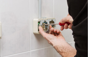 Мастер устанавливает розетку в квартире