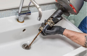 Сантехник устраняет засор в трубе