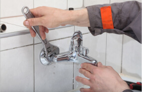 Мастер сантехник производит установку смесителя